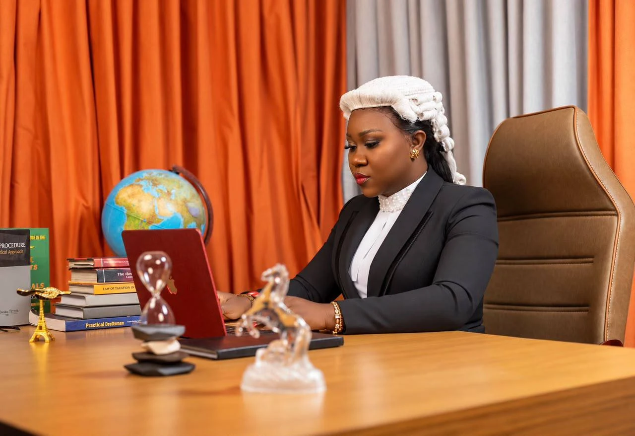 Ama in a barrister’s wig, working at a laptop at her desk