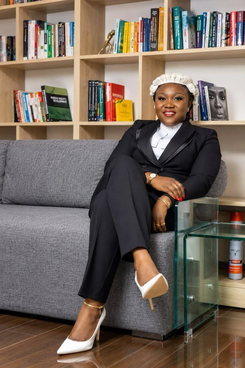 Ama smiling while seated in front of bookshelves, wearing her barrister’s wig and suit